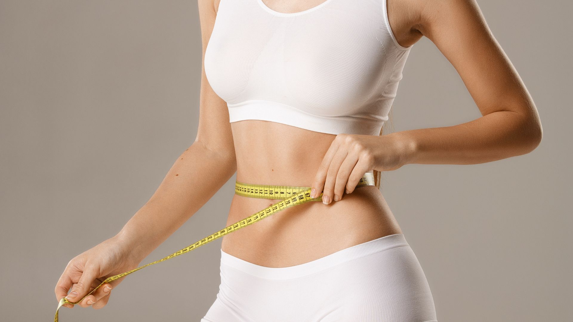 Abdominoplasty in Dubai - Woman Holding a Measuring Tap Around Her Waist